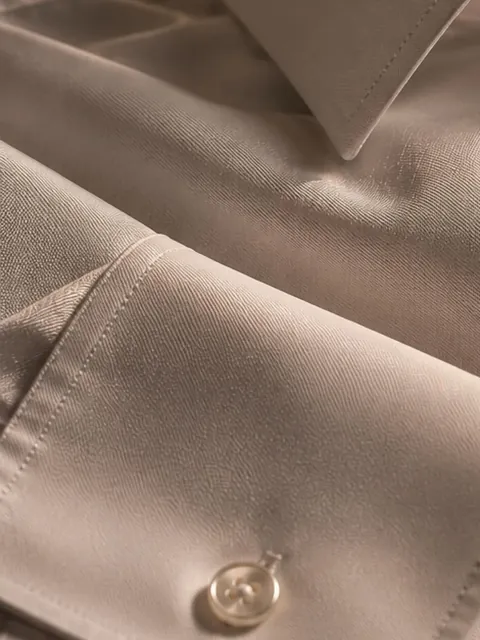 Le poignet d'une chemise blanche, avec son bouton nacré